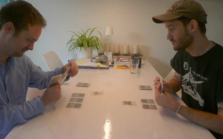 Zwei Männer spielen an einem Tisch Karten